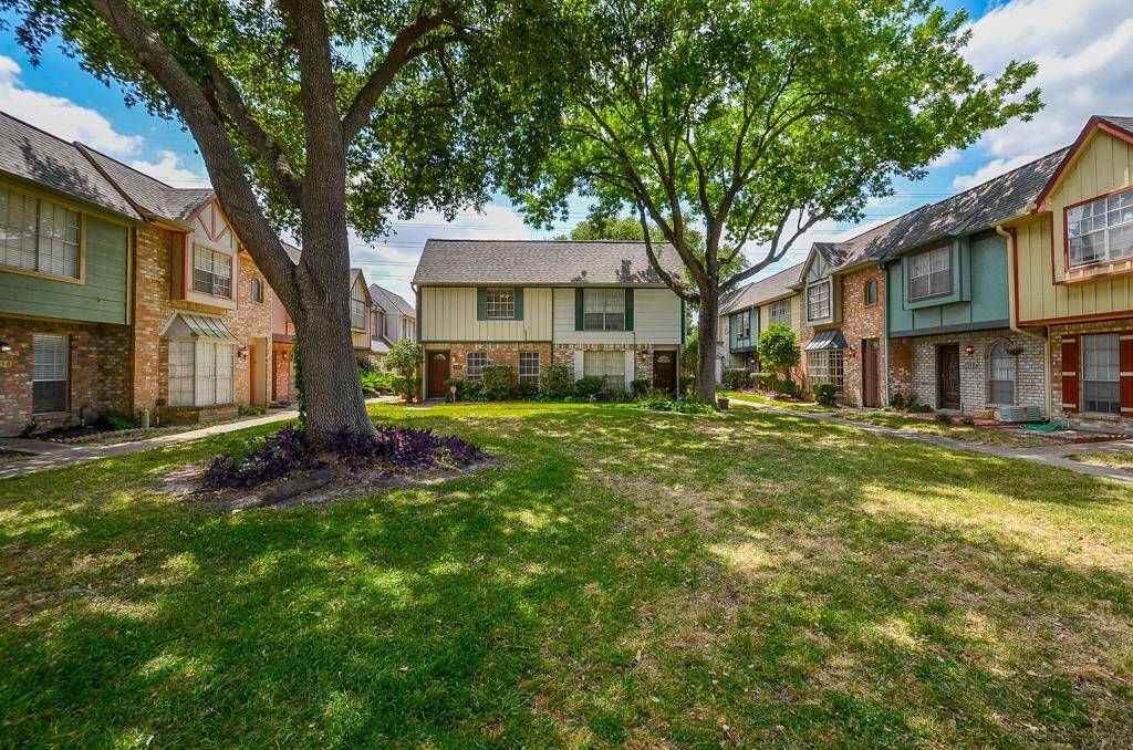 This photo showcases a charming townhouse community with mature trees and well-maintained lawns. The homes feature a mix of brick and siding exteriors, creating a cozy and inviting neighborhood atmosphere.