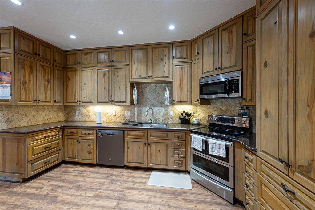 Beautiful epicurean kitchen with light paneled cabinets, granite countertops and recessed lighting
