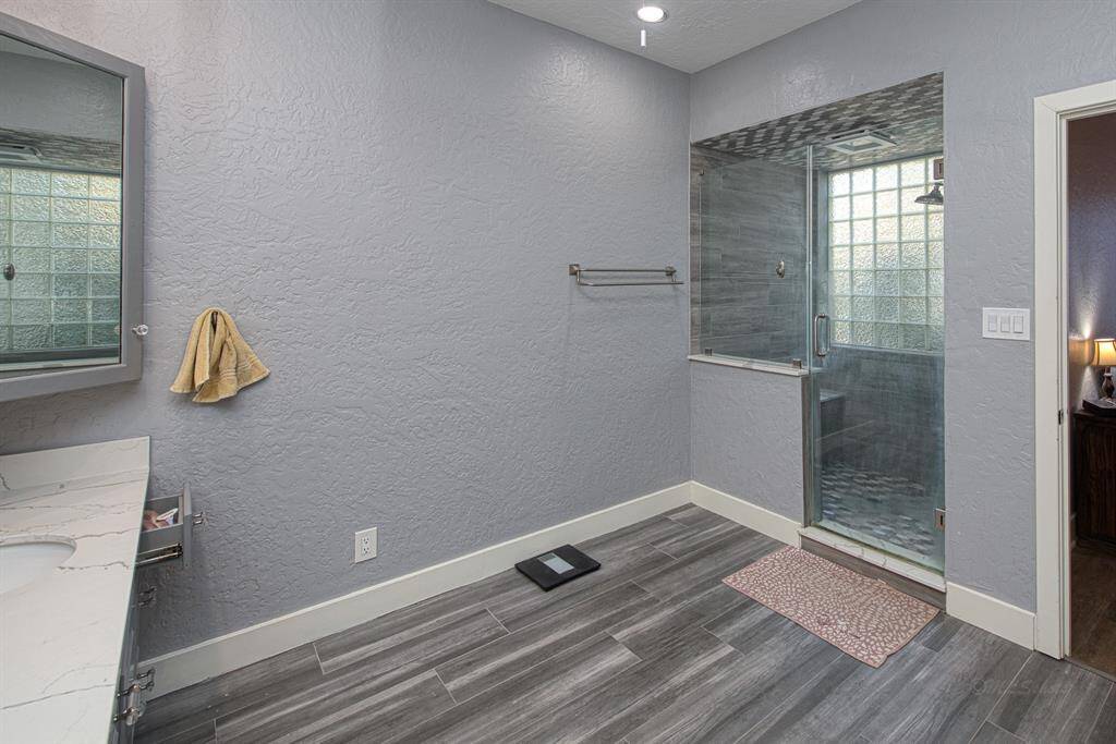 Large walk-in shower with privacy glass to let in the natural light. Decorative tile and bench seat