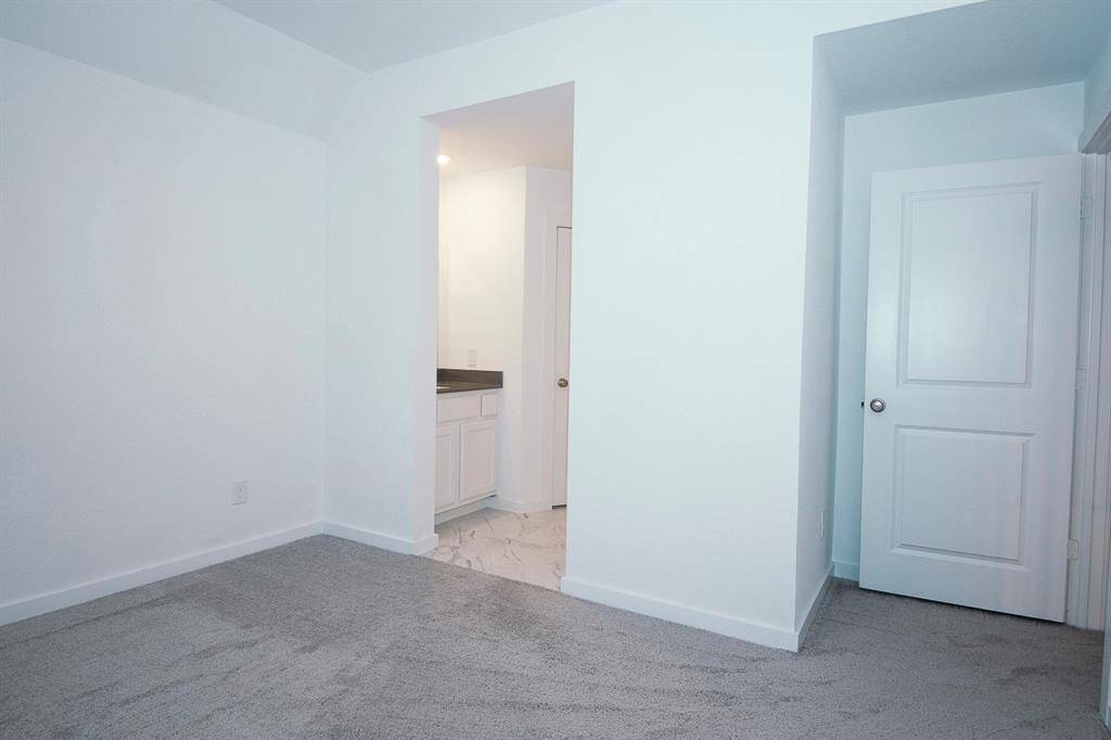 Cozy bedroom featuring plush carpeting, ample natural light, and a convenient en-suite vanity area.