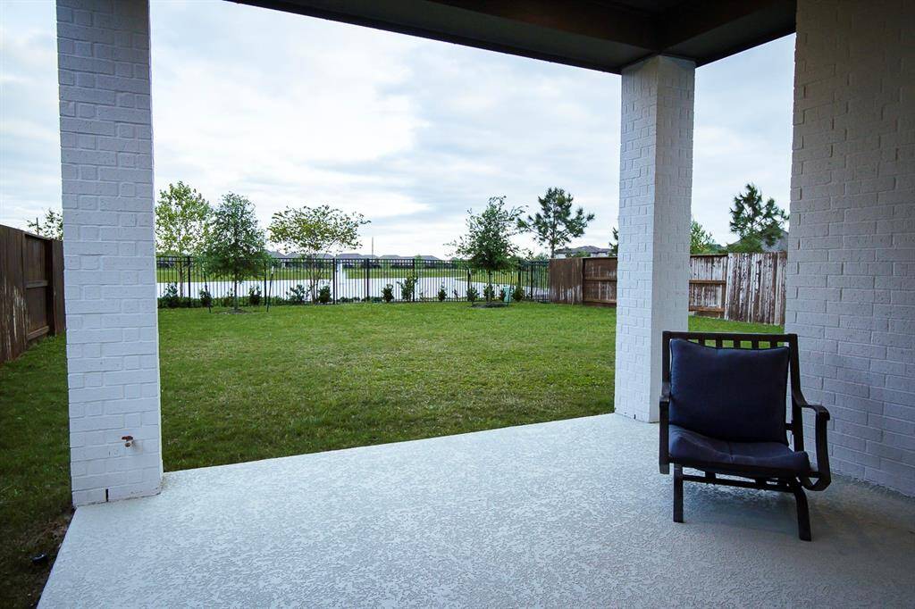 Spacious backyard with a covered patio, perfect for relaxing or entertaining, overlooking a lush lawn and serene water views.