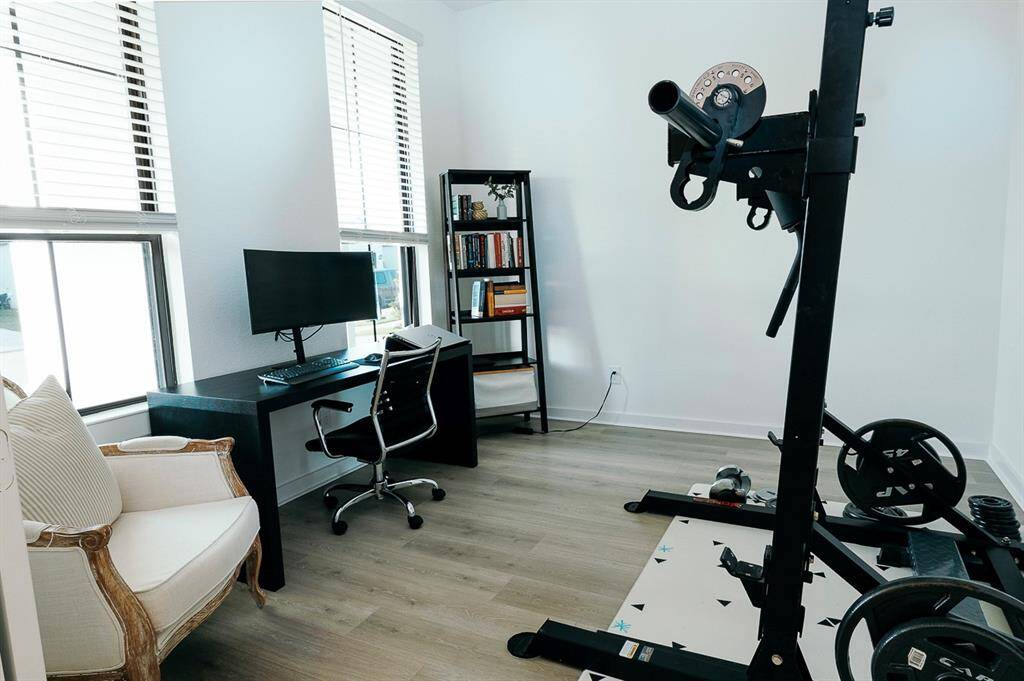 Versatile space ideal as a home office or personal gym, featuring ample natural light and a modern setup.