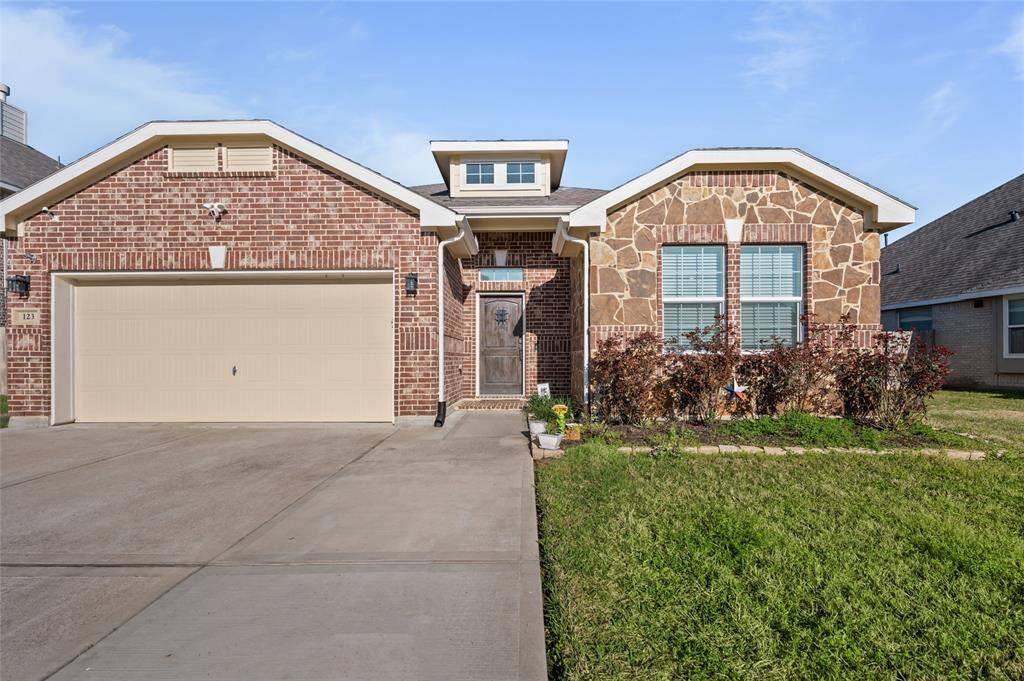 This charming home features a brick and stone exterior with a neat front yard and a two-car garage. The inviting entryway is highlighted by a wooden door and a well-maintained driveway.