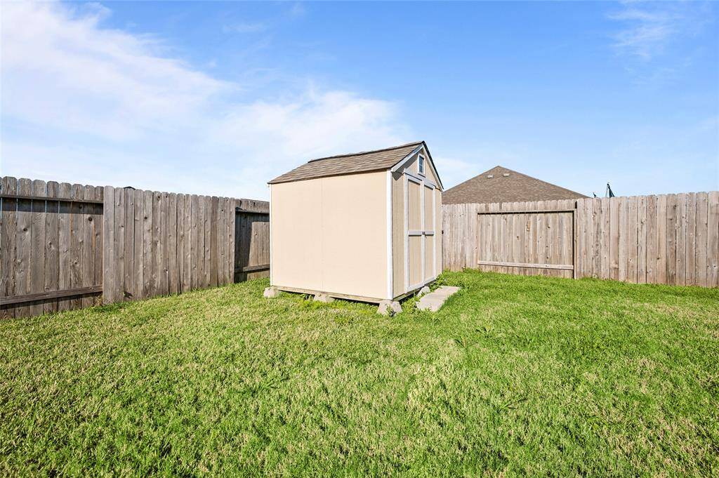 Fenced backyard with a small storage shed on a grassy lawn. The wooden fence provides privacy, and the space is open and well-maintained.