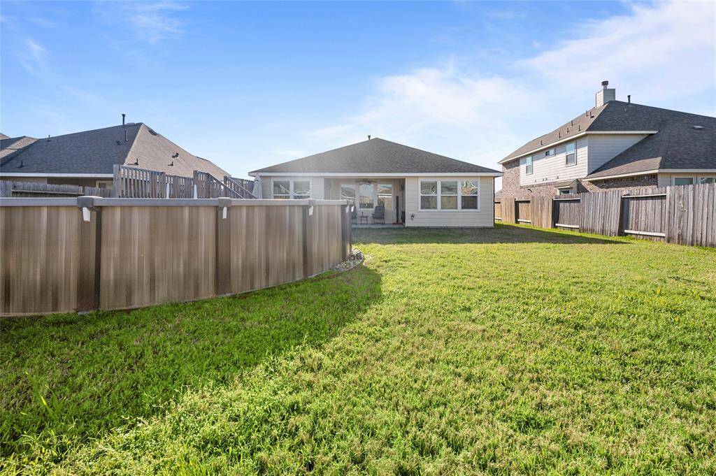 Spacious backyard with a well-maintained lawn, enclosed by wooden fencing. Features an above-ground pool and covered patio, perfect for outdoor activities and relaxation.