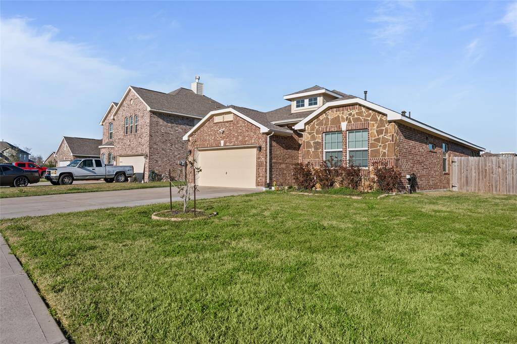 This charming brick home features a two-car garage and a well-maintained front lawn. The exterior has a mix of brick and stone accents, adding character. It's situated in a neighborhood with similar style homes and has a spacious driveway.