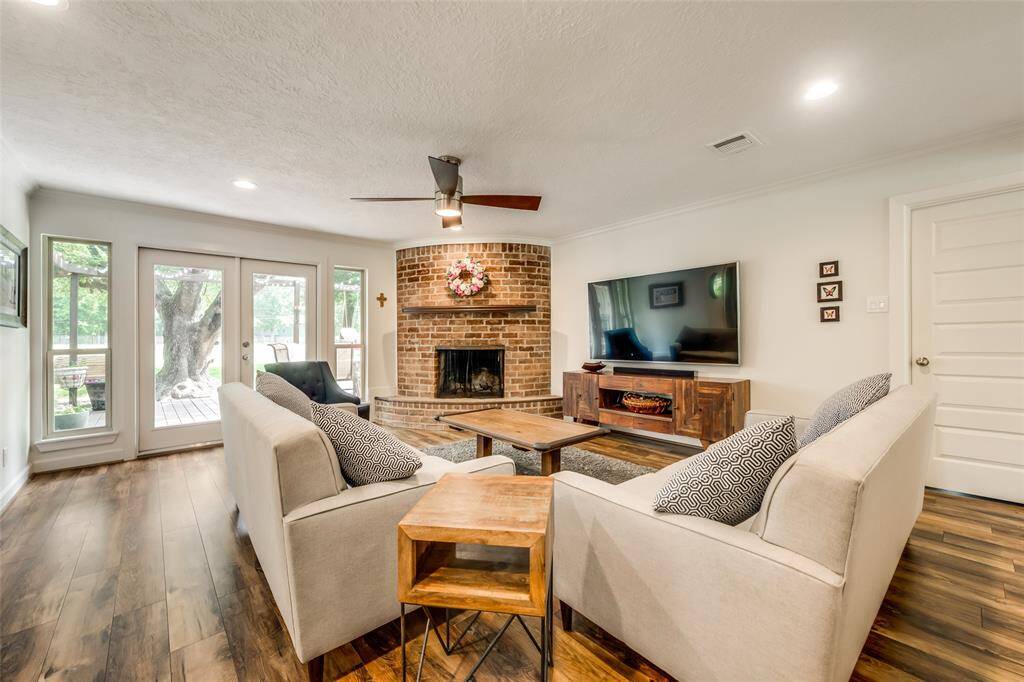 The den includes an upgraded ceiling fan, crown molding and an accent fireplace with brick hearth.