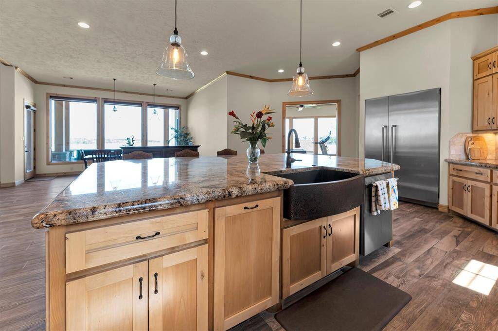High-end finishes fill this stunning island kitchen, where form meets function in every detail. Enjoy custom cabinetry with pull-outs and stylish hardware, sleek stainless steel appliances, gorgeous granite countertops, and tumbled stone backsplash highlighted by under-cabinet lighting. An upgraded farmhouse sink and chic pendant lights over the island offer the perfect blend of charm and practicality for everyday living and entertaining.