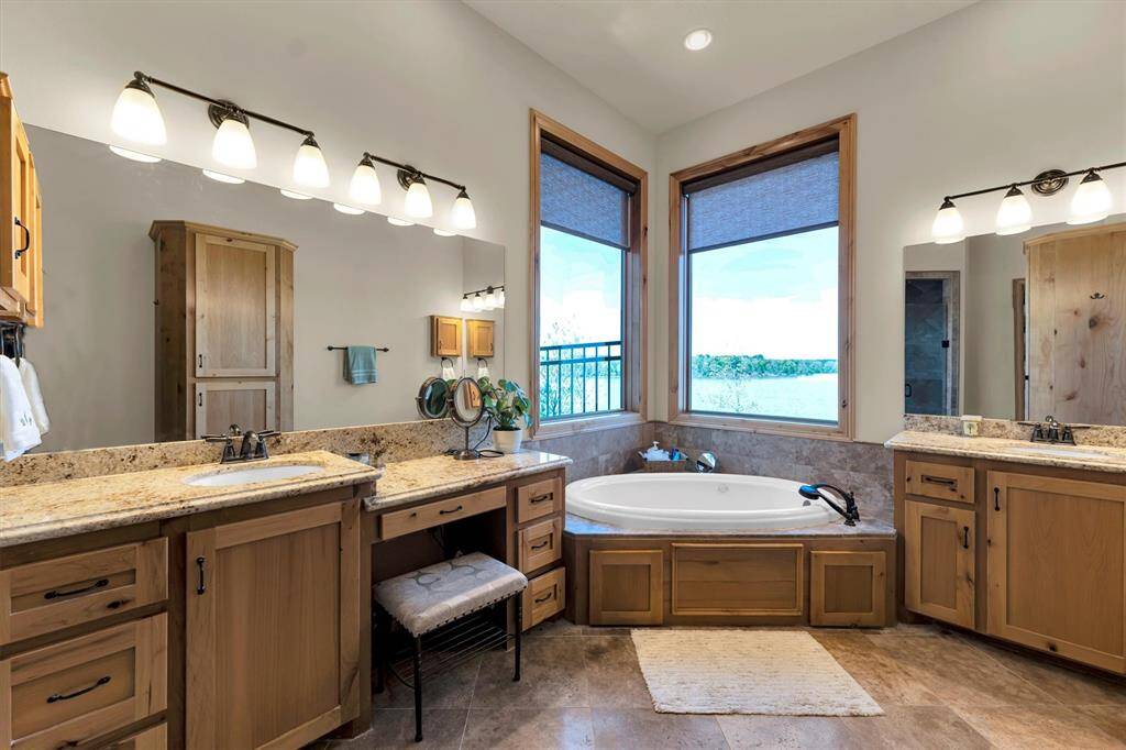 This luxurious ensuite offers everything you need to start the day feeling refreshed and inspired. Enjoy two separate granite-topped vanities with elegant lighting above, a deep jetted soaking tub for ultimate relaxation, and an oversized walk-in shower designed for both comfort and convenience.