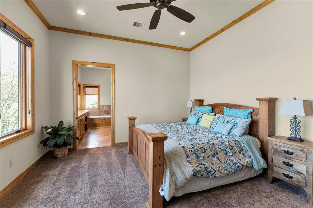 This inviting first-floor guest suite offers luxurious accommodations with stunning views, perfect for friends and family alike. Thoughtfully designed with plush carpet, neutral paint, and a raised ceiling with a cooling fan, it also features a spacious walk-in closet and a lavish ensuite bathroom for ultimate comfort and privacy.