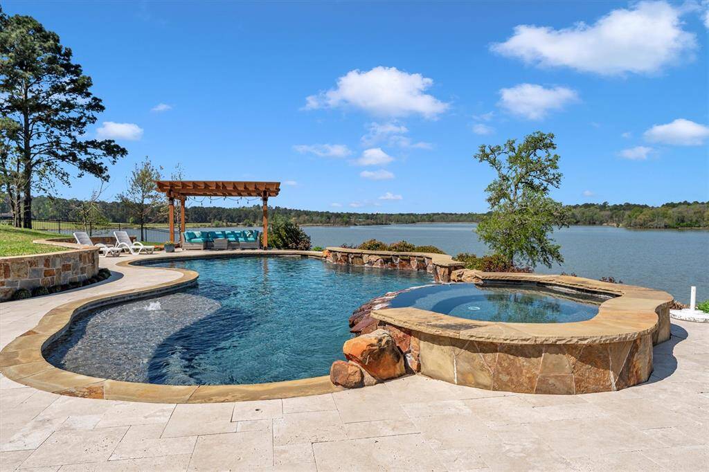 Make a splash in this stunning lakeside oasis featuring a sparkling pool and raised spa, heated by a dedicated 250-gallon propane tank for year-round enjoyment. Poolside seating, a summer kitchen, and serene lake views make it the ultimate space for relaxing, entertaining, and soaking up the sun.