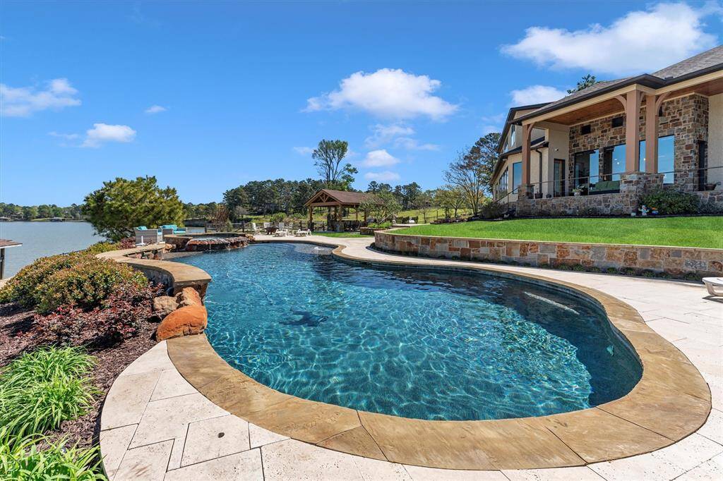 Take a dip—the water is perfect in this sparkling lakeside pool with a raised spa, ideal for both relaxing and entertaining. Whether you're soaking up the sun on the poolside lounge deck or hosting guests in the nearby summer kitchen, this outdoor retreat delivers unforgettable lakeside living.