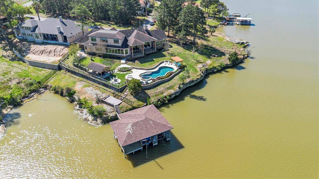 On a prime waterfront lot, this stunning lakeside property is company-ready with 4 spacious suites, 4.5 bathrooms, 2 game rooms, a chef’s island kitchen, open-concept dining, a dedicated study & a functional mud room. At the heart of the home, the impressive family room features a soaring ceiling & a striking stone gas-log fireplace. Step outside to enjoy resort-style living with a sparkling pool/spa, a fully equipped summer kitchen, multiple covered patios and a private boat house.