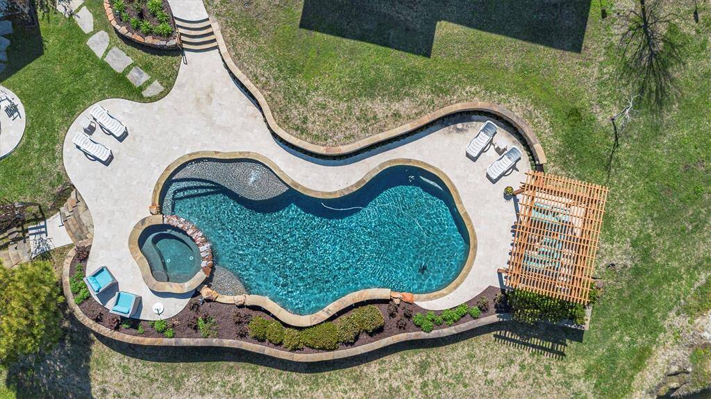 This aerial view showcases the sparkling pool surrounded by ample poolside seating, perfect for sunbathing, relaxing, and entertaining in style, all with breathtaking lake views as your backdrop.