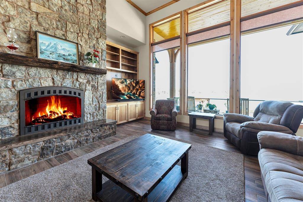 Unwind fireside in this inviting family room after a fun-filled day on the lake. Enjoy the warmth of the stone fireplace, custom built-ins, and breathtaking views of the patio, pool, and lake through picture windows that span the back of the open living and dining areas.