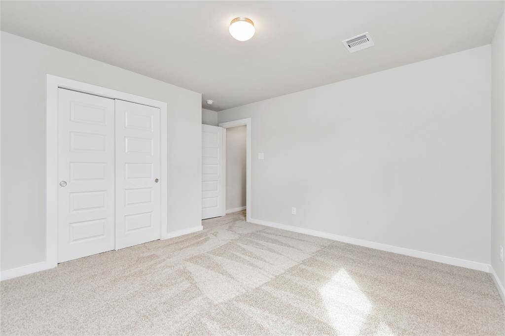 Secondary bedrooms showcase 5-panel doors adorned with modern hardware, large windows enhanced by privacy blinds, and spacious closets featuring sleek and contemporary finishes. Sample photo of completed home with similar floor plan. As-built interior colors and selections may vary
