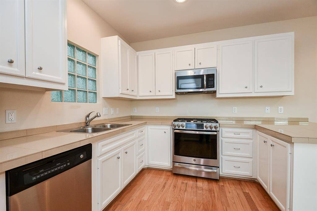 The large floor area is perfect for both cooks and helpers to happily coexist. Don't you love the art-deco like window over the sink and the soothing tile backsplash?