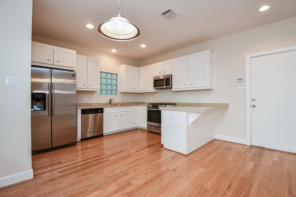 Gorgeous, white, compact cabinetry offers great storage space, with extended countertop, right, perfect for some stools, below. Shining stainless steel appliances add to the welcoming glow.
