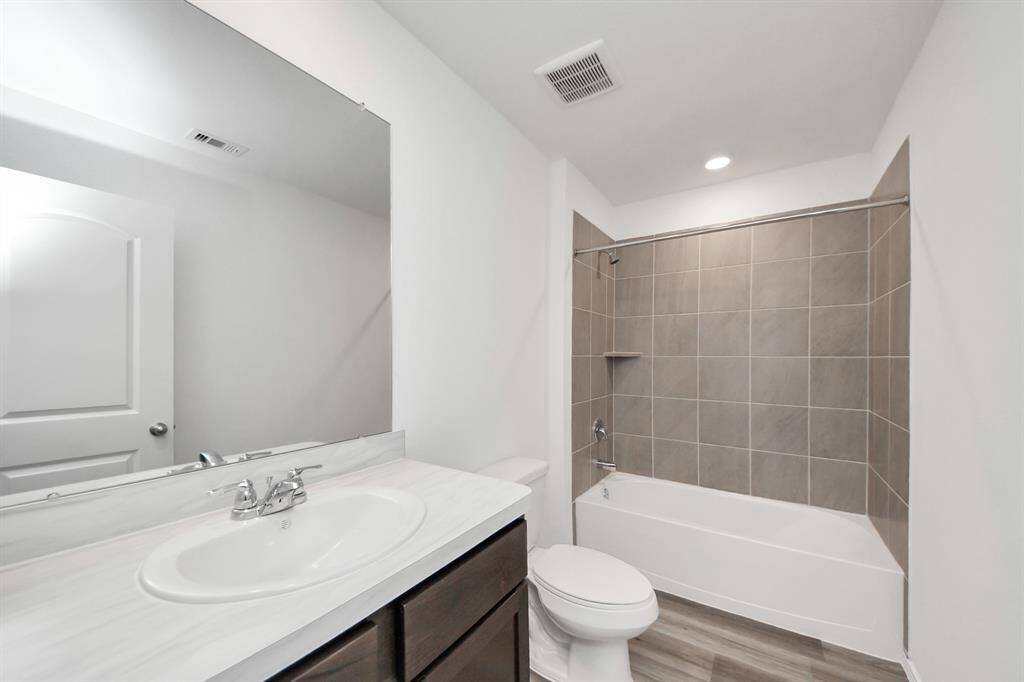 This bathroom features a modern design with a sleek vanity, large mirror, and a bathtub with neutral tile. The space is well-lit and has a clean, contemporary feel.