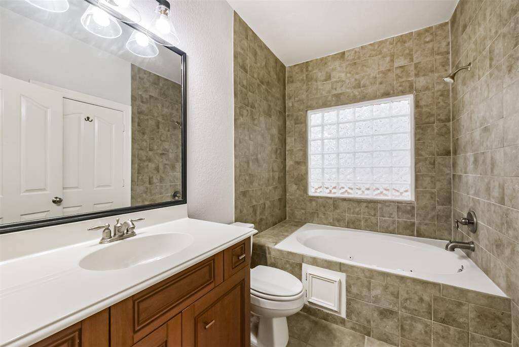 First floor full bathroom with a shower/garden bath combo and ample vanity storage. The large walk in closet is opposite the mirror.
