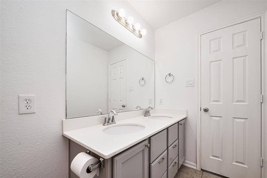 This bathroom features a clean, modern design with a dual-sink vanity and ample cabinet storage. It has a large mirror, sleek fixtures, and a neutral color palette, creating a bright and inviting space.