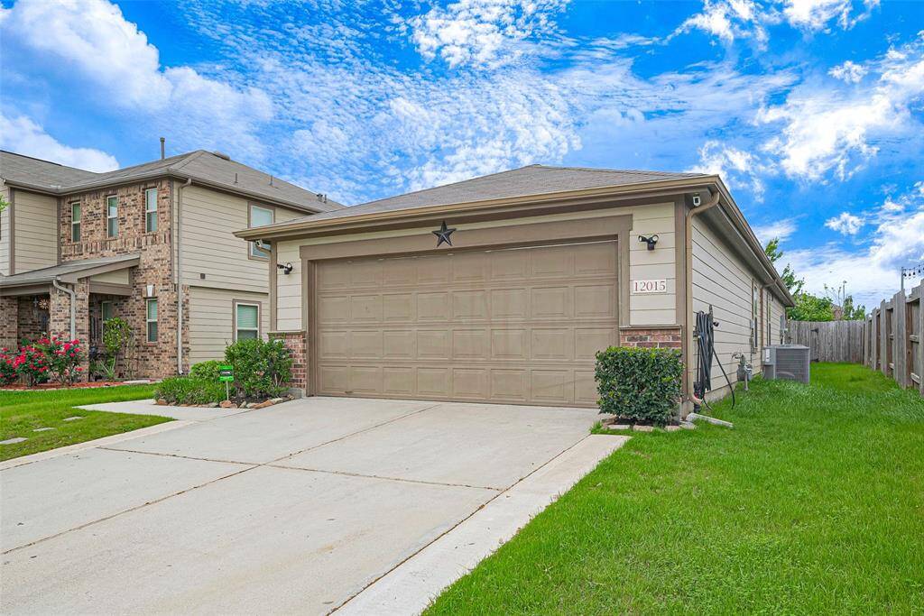 This photo features a modern two-story home with a brick and siding exterior. It has a large two-car garage, well-maintained lawn, and a fenced backyard. The house is situated in a suburban neighborhood, offering a clean driveway and attractive curb appeal under a bright blue sky.