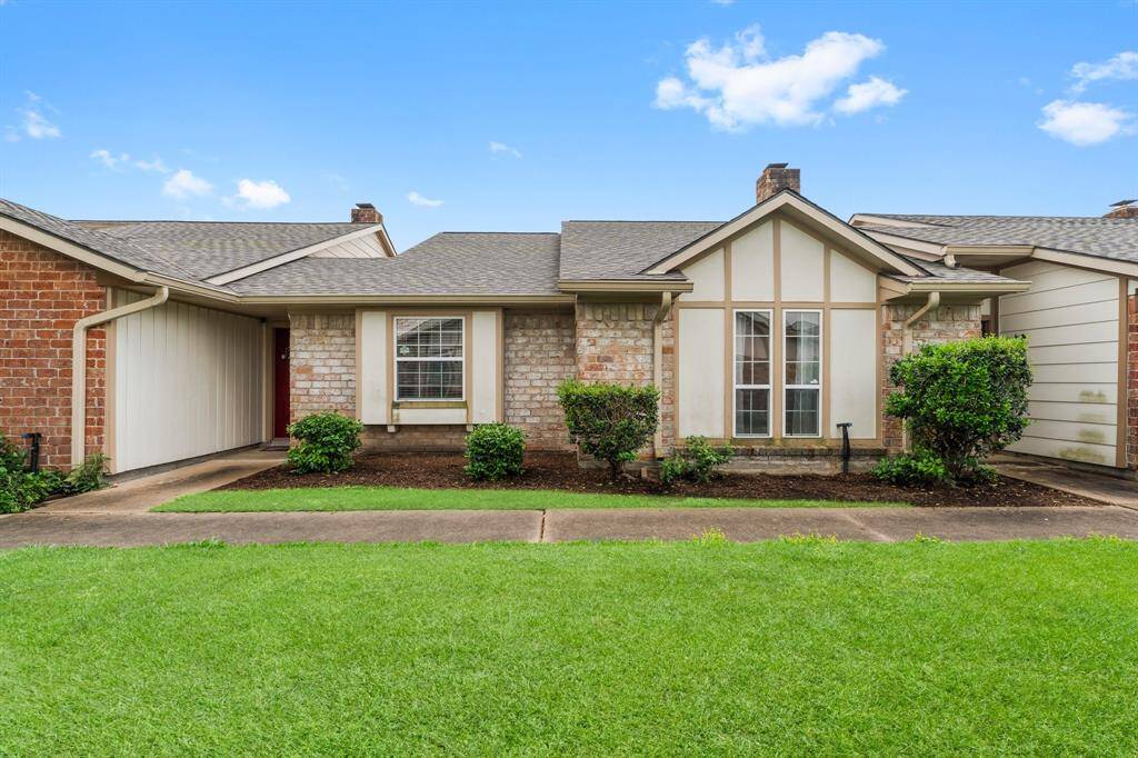 Beautiful single-story condo featuring a brick and Tudor-style exterior, large windows, and lush green lawn—perfect for relaxed living.