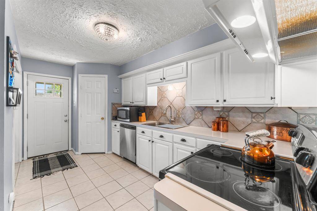 Charming kitchen with crisp white cabinetry, stainless steel appliances, and a stylish tile backsplash—offering both functionality and warmth for everyday cooking.