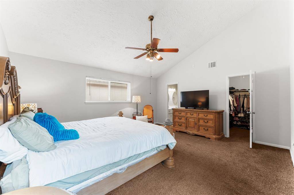 Spacious primary bedroom with vaulted ceilings, plush carpet, and plenty of natural light—complete with a walk-in closet, ensuite bath, and room for a cozy sitting area.