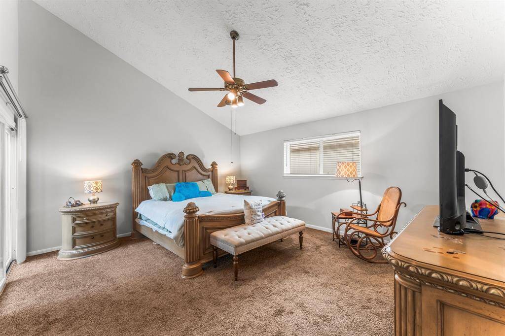 Elegant primary bedroom with vaulted ceilings, classic wooden furnishings, and soft natural lighting—offering both comfort and timeless charm.