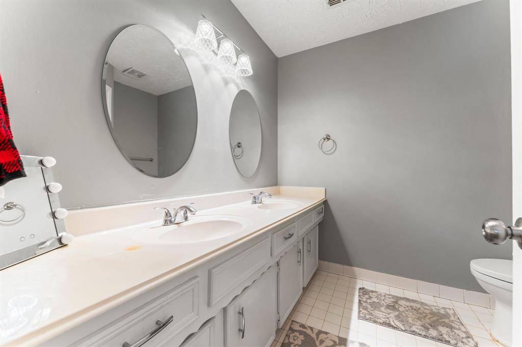 Bright and functional bathroom featuring dual sinks, updated fixtures, and ample cabinet storage—perfect for a streamlined morning routine.