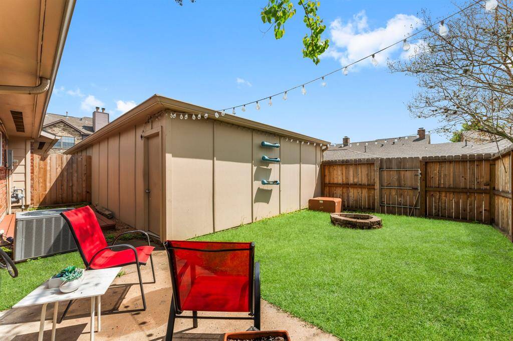 Charming backyard retreat with a lush lawn, cozy fire pit, string lights, and a spacious storage shed—ideal for relaxing evenings and weekend gatherings.