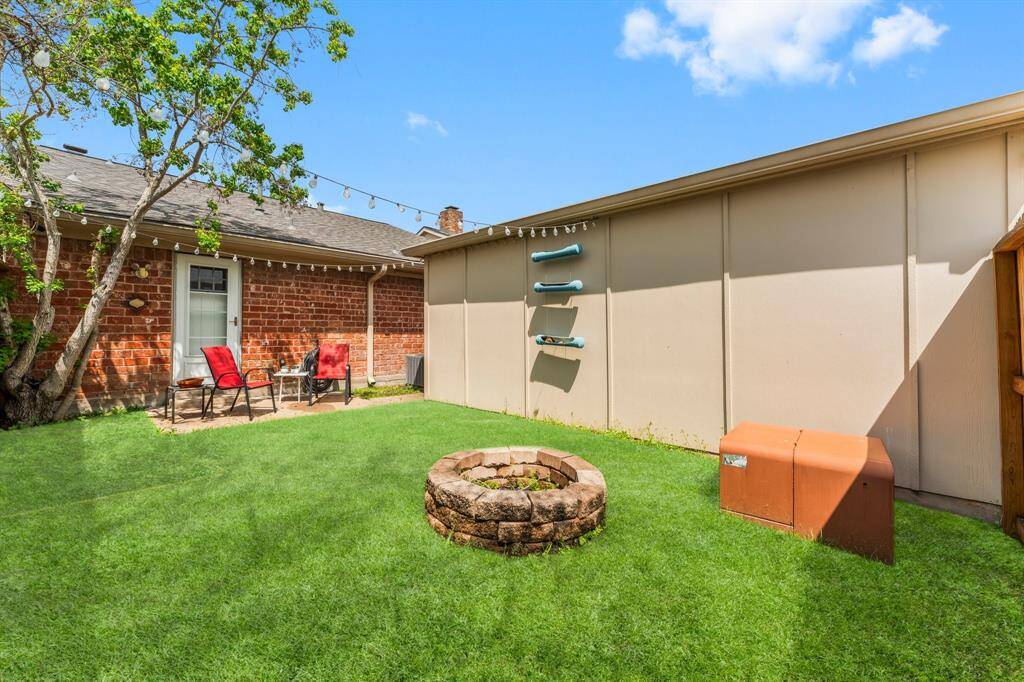 Sunny and private backyard space with a cozy fire pit, string lighting, and a seating area—perfect for entertaining or enjoying peaceful evenings under the stars.