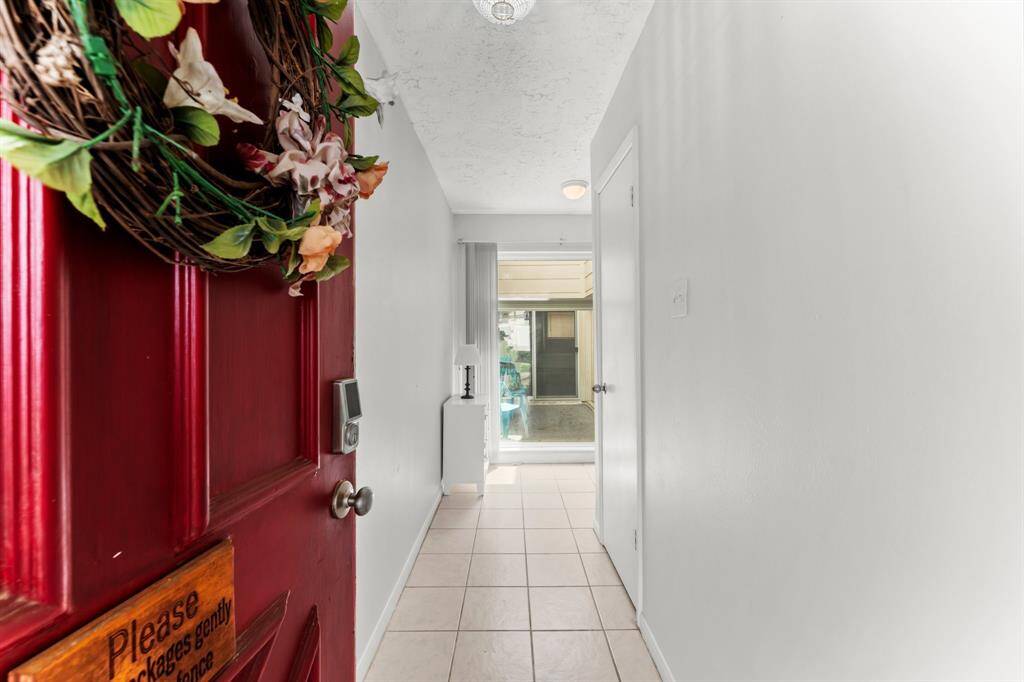 Welcoming entryway with a pop of color from the red front door, clean light colored walls, and tiled flooring leading to a bright, open living space.