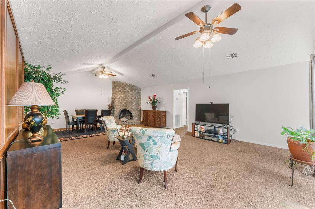 Airy and open living-dining space with vaulted ceilings, neutral walls, and a stunning brick fireplace—perfect for creating your ideal home ambiance.