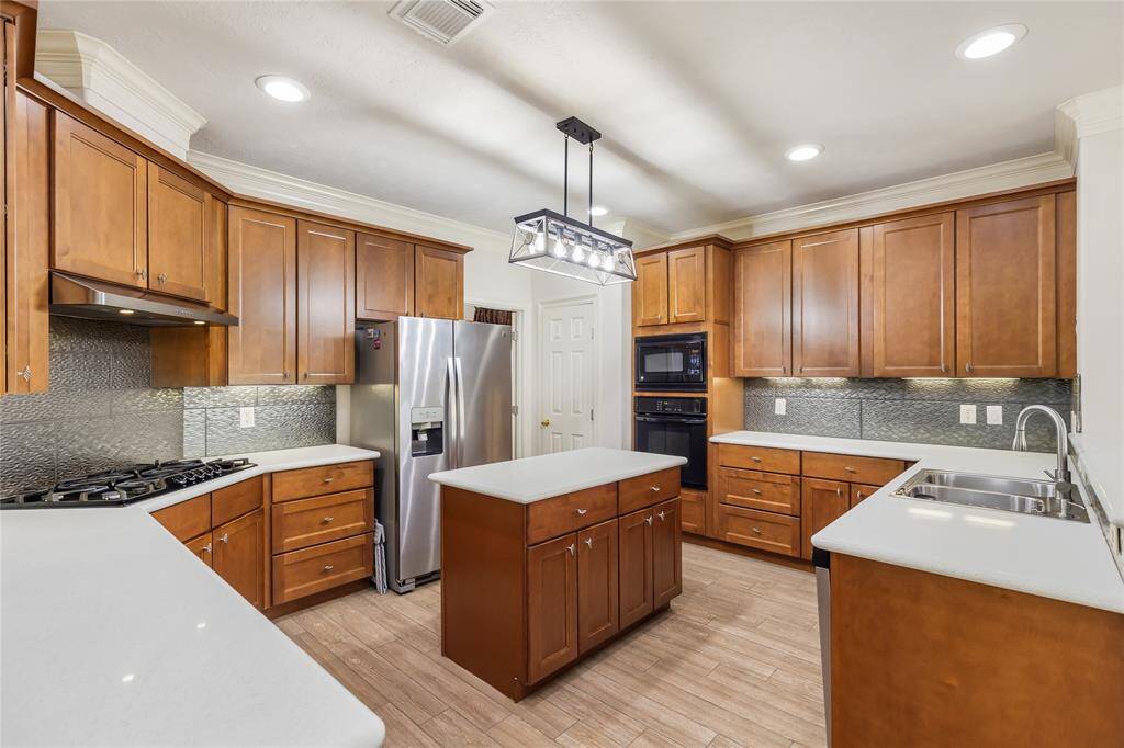 This well-outfitted Kitchen offers ample cabinet and counter space, built-in oven and microwave, gas cooktop, and new farmhouse-style light over the convenient island with additional storage.