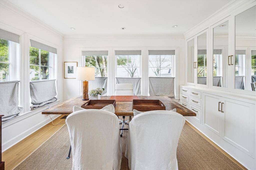 This home office, featuring French doors and custom cabinetry, is bathed in natural light from windows that overlook both the front and side streets.