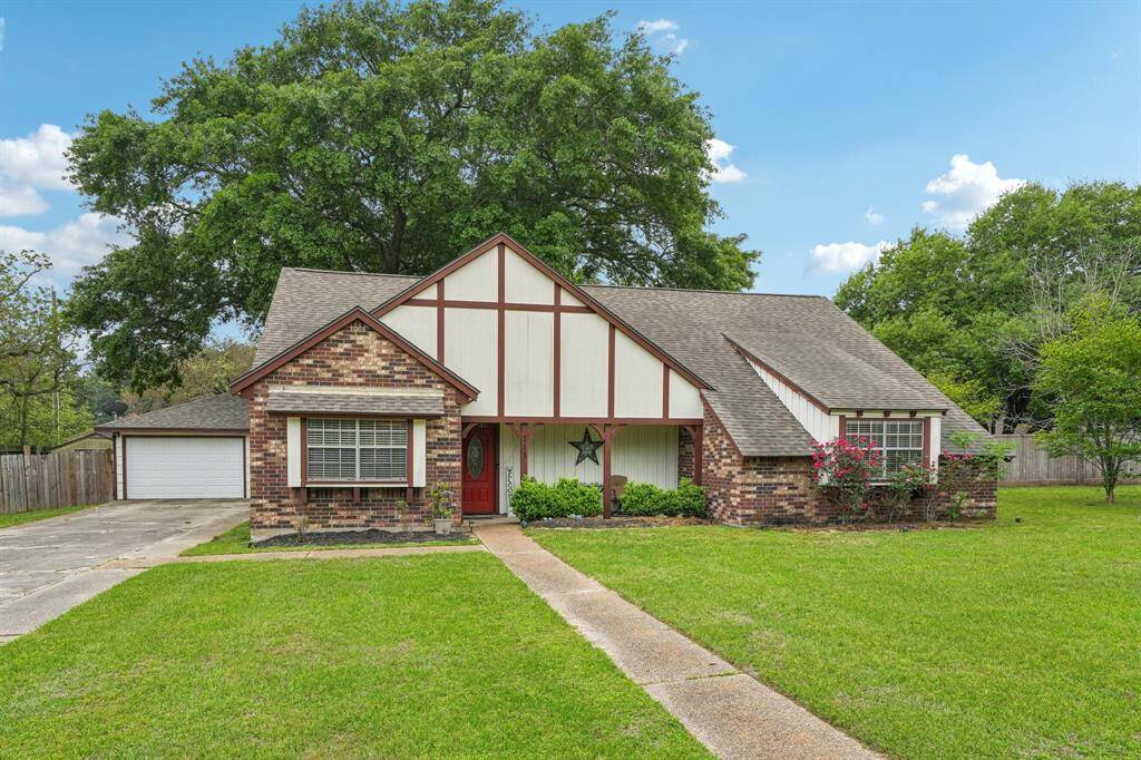 This charming home features a classic Tudor-style exterior with brick and timber accents. It has a well-maintained lawn, a welcoming front entrance, and a separate garage. The property is surrounded by mature trees, offering a serene and private setting.