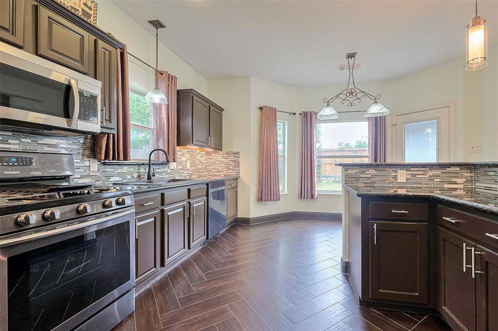This is a two-story brick home with a welcoming front entrance. It features a well-maintained lawn, mature tree, and a two-car garage. The large windows offer plenty of natural light.