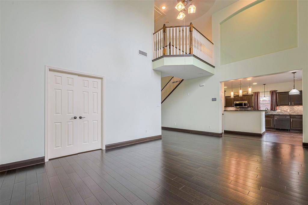 This photo shows a two-story brick house with a double garage, a well-maintained driveway, and a small front yard. It is situated in a suburban neighborhood with neighboring similar-style homes and features a large tree offering shade.