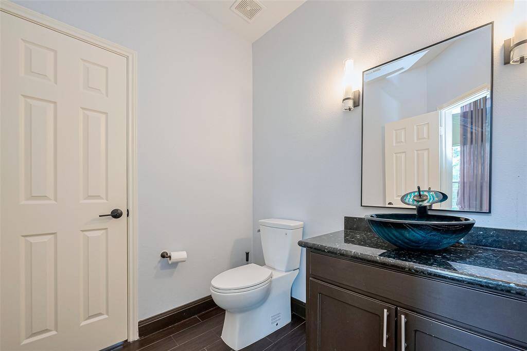 This room features dark hardwood floors, a large window with elegant drapes, and a ceiling light fixture, offering a bright and inviting space.