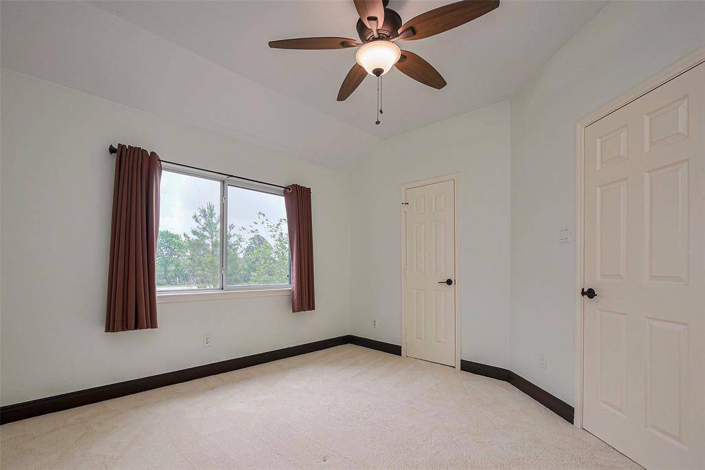 This photo showcases a bright, airy staircase area with beige carpeting and dark wood railings. It features large windows with curtains, allowing natural light to flood in, and a modern ceiling light fixture. The space has a welcoming, open feel.