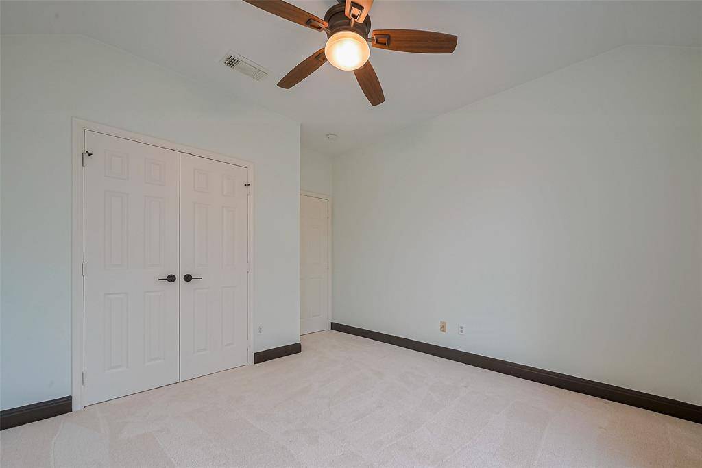 Bright, open room with dark hardwood floors and large windows letting in natural light. The space features a modern light fixture and neutral walls, ideal for a dining or living area.