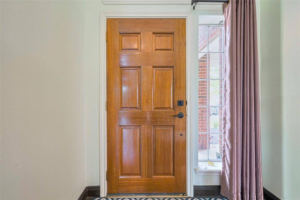 This two-story brick home features a welcoming entryway with a covered porch. It has a two-car garage and a spacious driveway. The front yard is landscaped with a tree and shrubs, adding to the curb appeal.