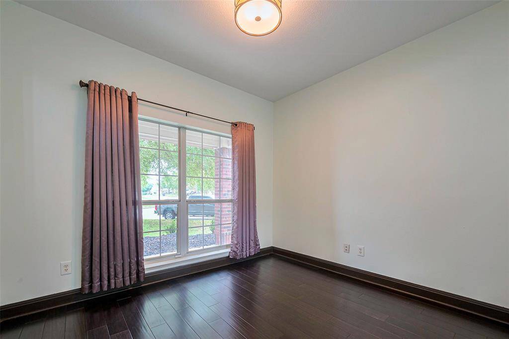 A spacious two-story brick home with a double garage, nestled in a suburban setting. The property features a well-maintained lawn with young trees and a curved driveway.