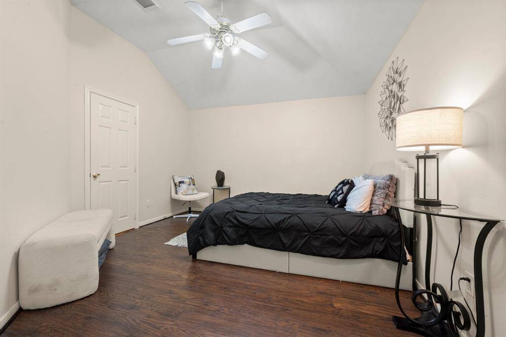 This bedroom features a high ceiling with a ceiling fan, hardwood floors, and neutral walls.