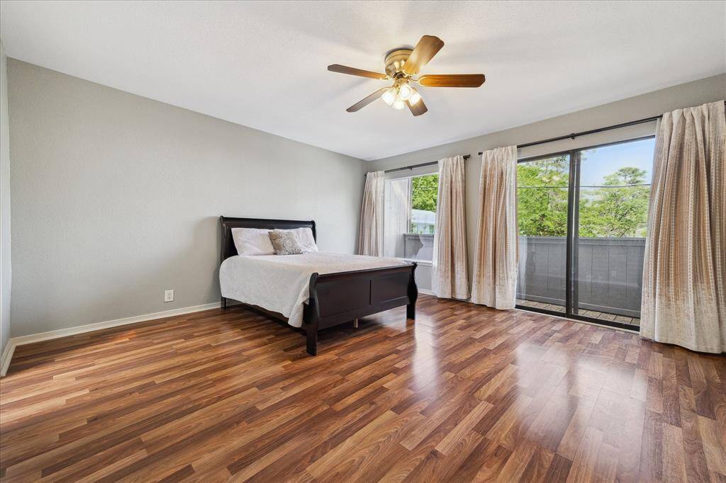 Upstairs spacious primary bedroom with a wall of closets and a wall of windows/sliding doors opening to a balcony