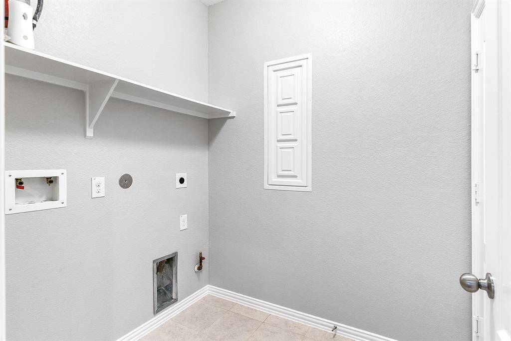 Laundry room with gas and electric hookups. Located downstairs. Underneath the panel on the wall is every water cut off valve to the home. Garage access is to the right.