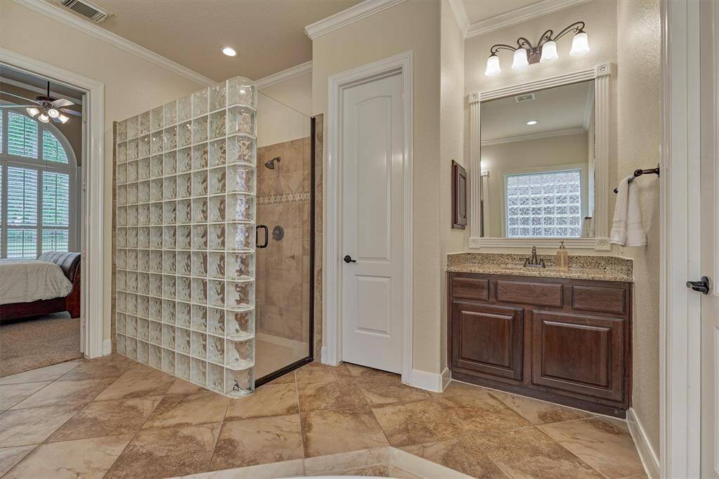 Luxurious primary bathroom is designed with elegance and offers dual vanities with granite countertops and huge walk-in shower.