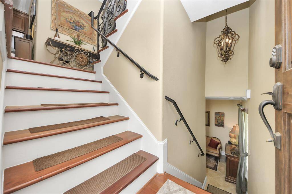 The room features recessed lighting, crown molding, and a glass-paneled door leading to another cozy room with natural light and warm decor.